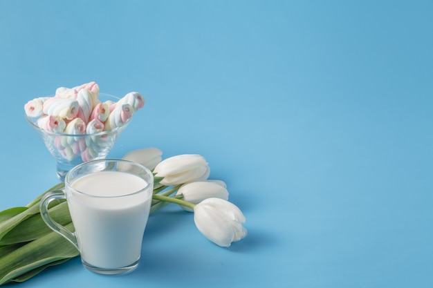 Mazzo della primavera dei tulipani bianchi, caramelle gommosa e molle e tazza di latte