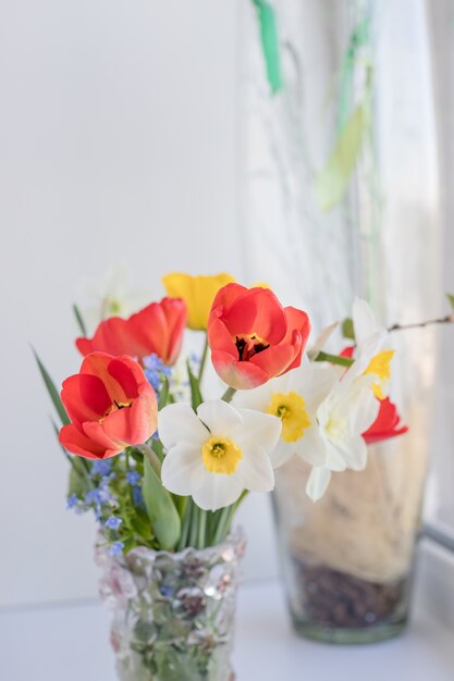 赤いチューリップと水仙の春の花束。新鮮な花。花瓶の白いbackground.delicate花に分離された新鮮な春の花のカラフルな花束。