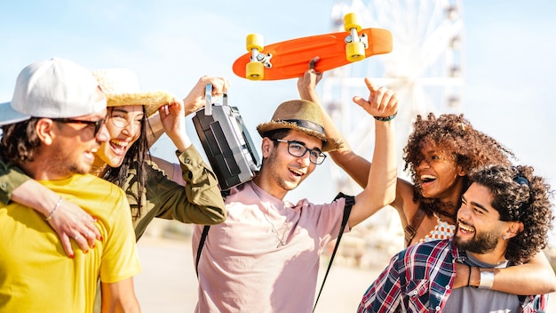 Photo spring break life style concept with millenial friends having fun together at summer festival by ferris wheel happy guys and girls students cheering at sunset on vacation days bright warm filter