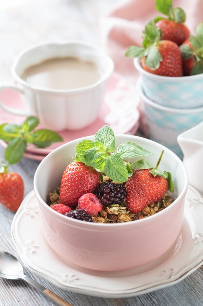 Spring Breakfast with granola and fresh strawberries and lychee and flowers on wooden background.