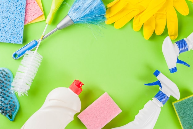 Spring cleaning concept with supplies, house cleaning products pile. Household chore concept, on green background top view copy space