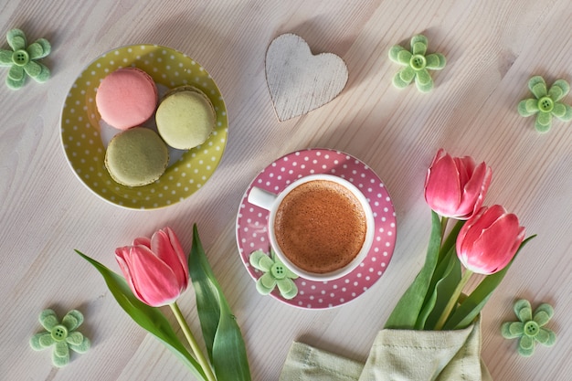 Весенний кофе фон. Macarons, эспрессо в розовой чашке, фрезии и розовые тюльпаны