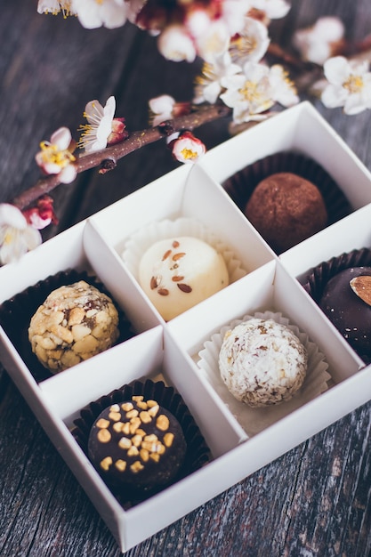 Foto collezione primaverile di cioccolatini fatti a mano con caramelle e fiori di ciliegio decorazione su fondo di legno rustico.