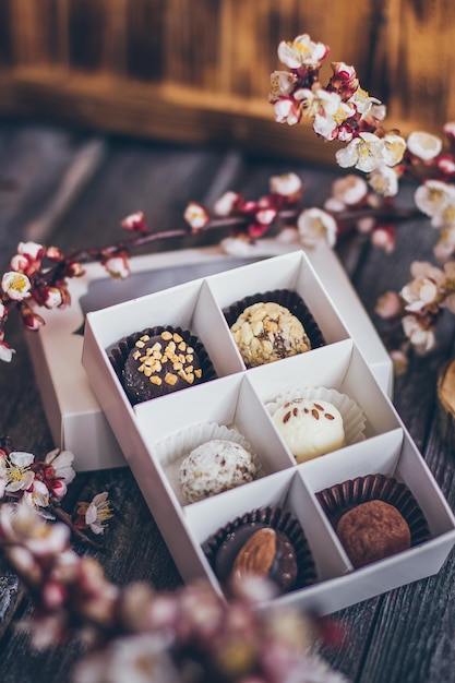 Foto collezione primaverile di cioccolatini fatti a mano con caramelle e fiori di ciliegio decorazione su fondo di legno rustico.