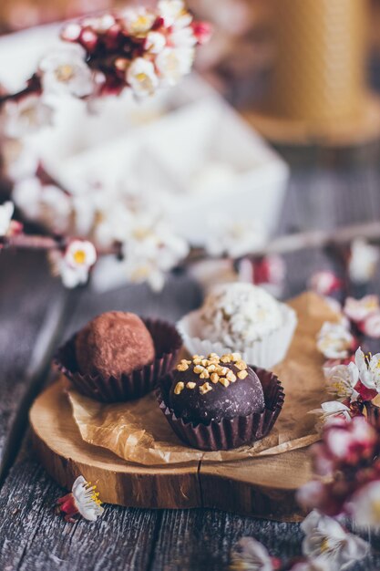 写真 素朴な木製の背景に手作りチョコレートボンボンキャンディーと桜の花の装飾の春のコレクション。