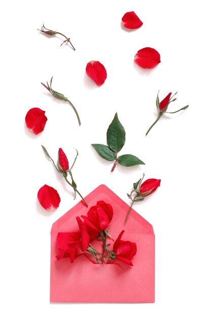 Spring composition with envelope and red roses over white background top view