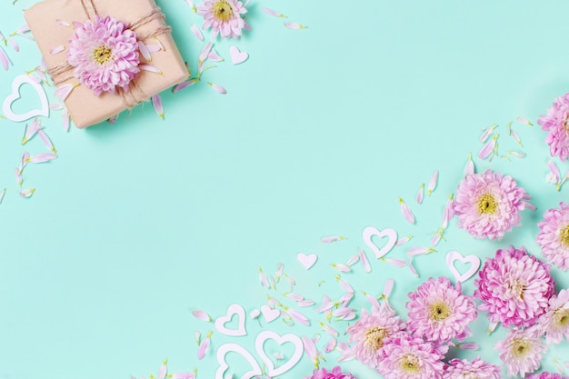 Spring composition with flowers, petals, hearts and gift box on a pastel  background