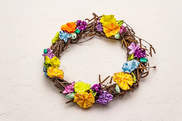 Spring composition of a wreath of birch branches and craft colorful flowers