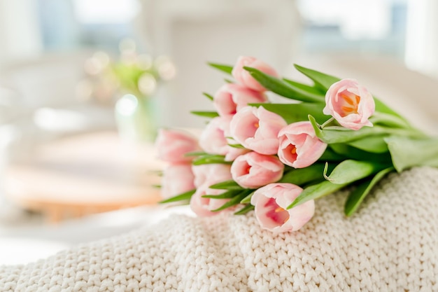 Spring concept with pink tulips lying on a blanket in a bright modern interior A beautiful banner