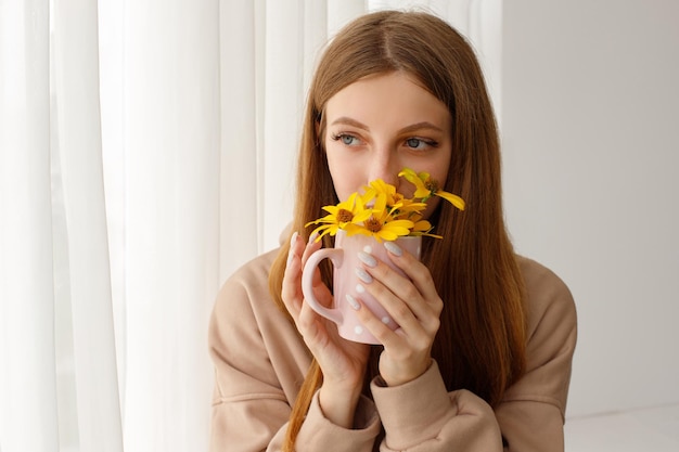Весенняя концепция женщина с желтыми цветами в чашке травяного чая