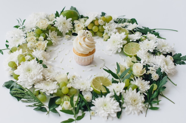 花と果物の白い背景の上の春のカップケーキ