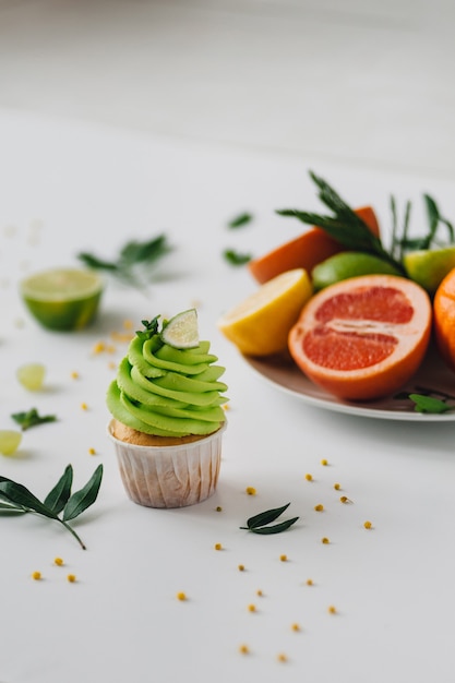 Spring cupcake on a white with flowers and fruits around.