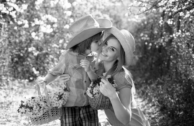 Photo spring family outdoor mother son family at spring day on picnic family mom with kid boy sitting on the grass in park with basket of flower bloom blossom