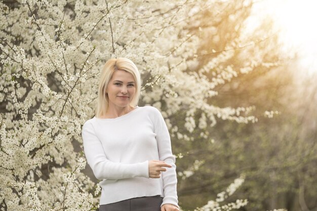 Spring fashion girl outdoor portrait in blooming trees. Beauty Romantic woman in flowers. Sensual Lady. Beautiful Woman Enjoying Nature. Romantic beauty in fantasy orchard.