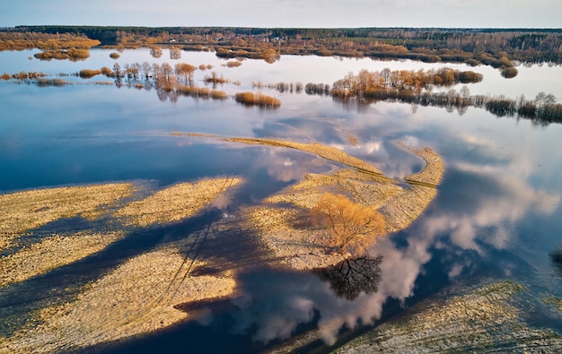 写真 春の洪水田園風景木々草原茂みフィールド高水浸水下の田舎道空雲夕方の光に反射フレセットオーバーフロー空撮氾濫原エリア