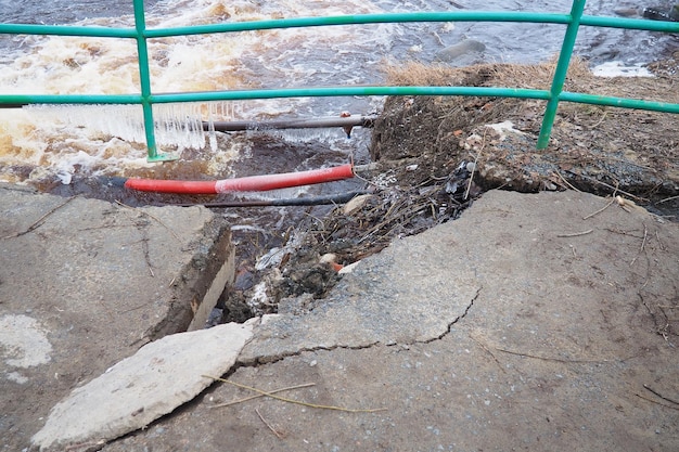 Photo spring flood rushing water in the river dark ferrous water rushes in the stream karelia lososinka river in spring floods tsunami and climate change destroyed bridge with pipes weather disaster