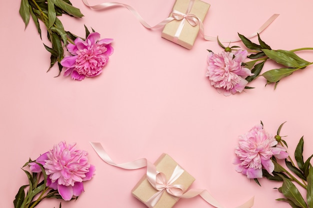 Spring floral composition of peonies and gifts on a white and pink table 