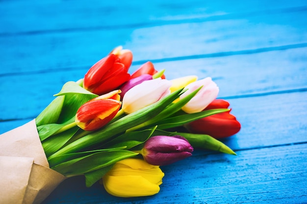 Bouquet di fiori primaverili bellissimi tulipani su legno rustico colore brillante sfondo blu turchese vista dall'alto piatta spazio per la copia