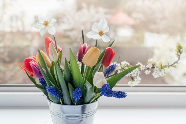 Bouquet di fiori di primavera sul davanzale della finestra, la festa della donna e la cartolina d'auguri di pasqua