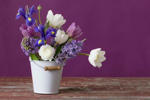 Spring flowers in bucket on pink background