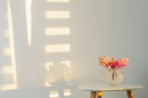 Spring flowers in glass vase on background white wall in sunlight