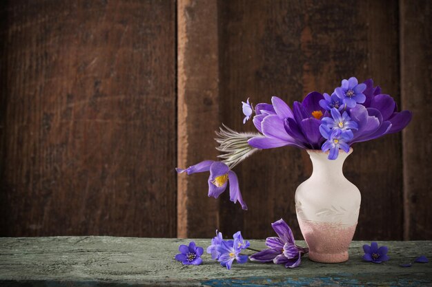 Фото Весенние цветы в вазе на деревянном фоне