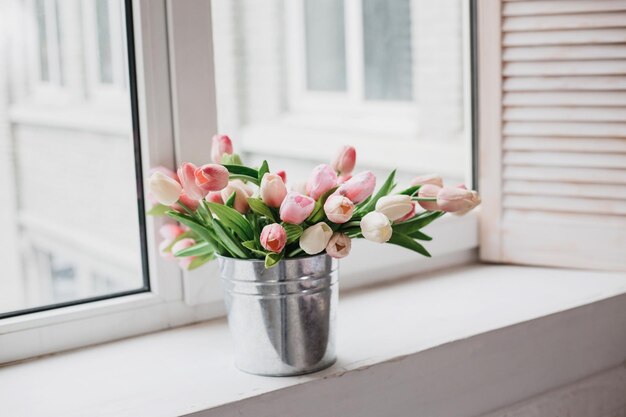 Spring flowers in vase on breakfast tray. White tulips in a vase in a rustic interior. Cozy apartme