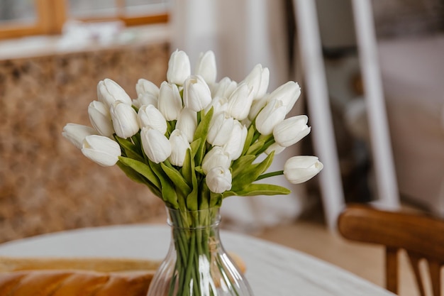 Spring flowers in vase on breakfast tray. White tulips in a vase in a rustic interior. Cozy apartme