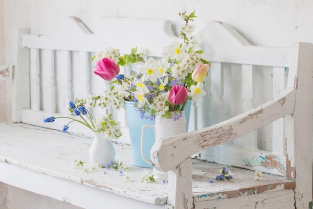 Spring flowers in vintage white interior with old wooden bench