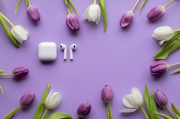 Spring fresh tulips and wireless headphones pods on violet background