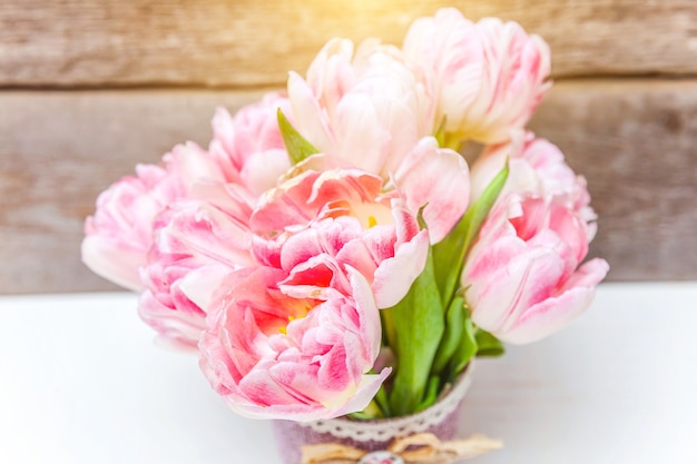 봄 인사말 카드. 나무 배경에 신선한 빛 파스텔 핑크 튤립 꽃의 꽃다발