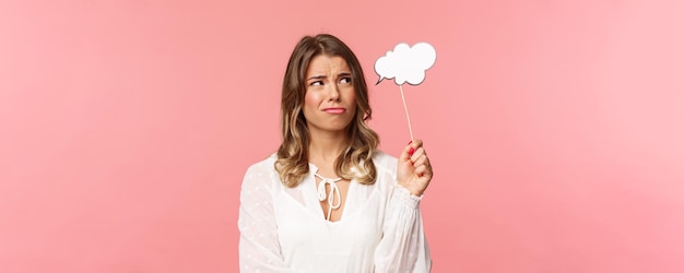 Spring happiness and celebration concept Closeup of skeptical and doubtful goodlooking blond girl holding commend cloud near head as if having thought grimacing and squinting from dislike