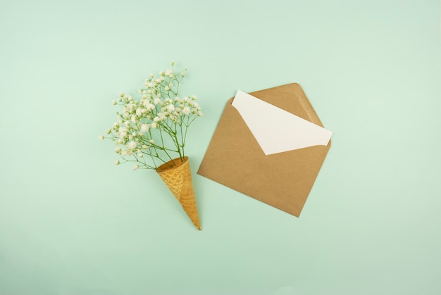 Spring is coming concept. A blank in a brown envelope with fresh flowers in a waffle cone.