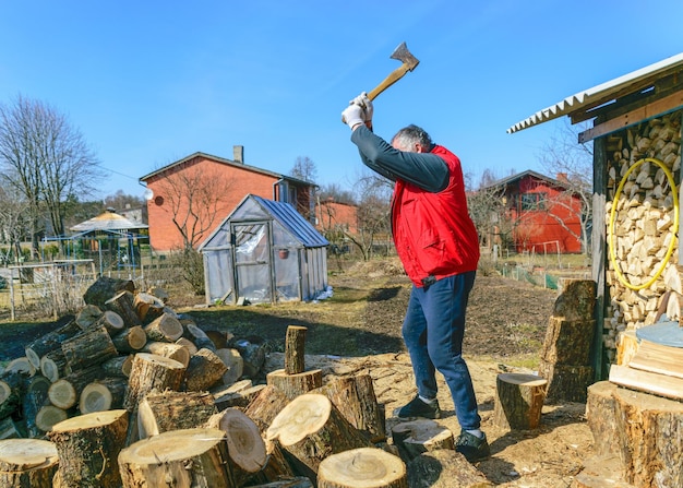 Photo spring landscape with a man in a red vest a man in his yard splits firewood climate change heated energy energy crisis