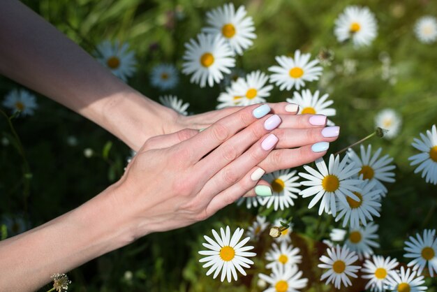 Spring manicure on short nails. Female hands on a chamomile. Care for hands.