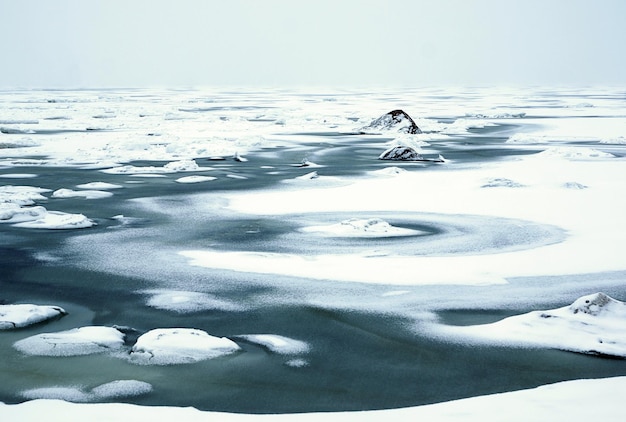 Foto scioglimento primaverile del ghiaccio sulla baia, inizio primavera, l'acqua blu si mostra attraverso il ghiaccio e la neve bianca