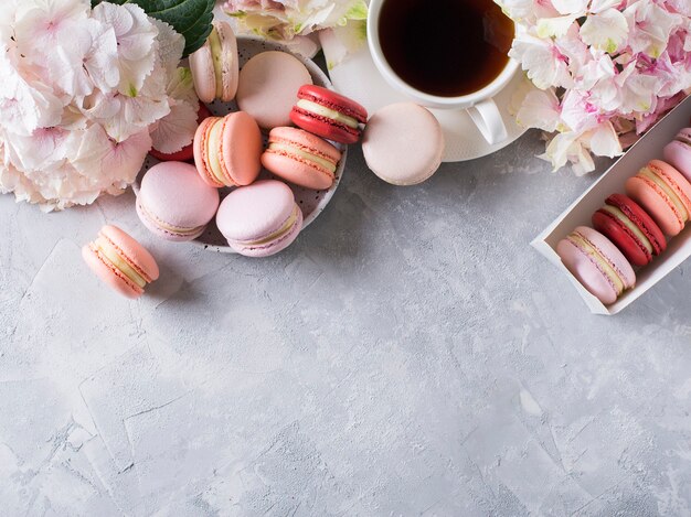 Spring mood still life with macaroons, flowers and cup of coffee on grey