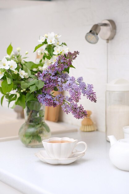 春の朝明るいキッチン白い花の花束白いお茶そして緑茶のグラス