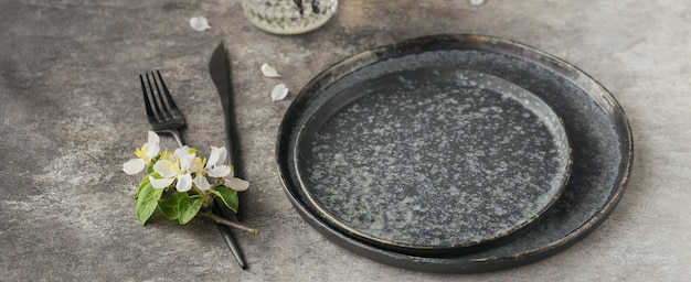 Spring place table setting with blossoming apple tree branches and flowers on grey table