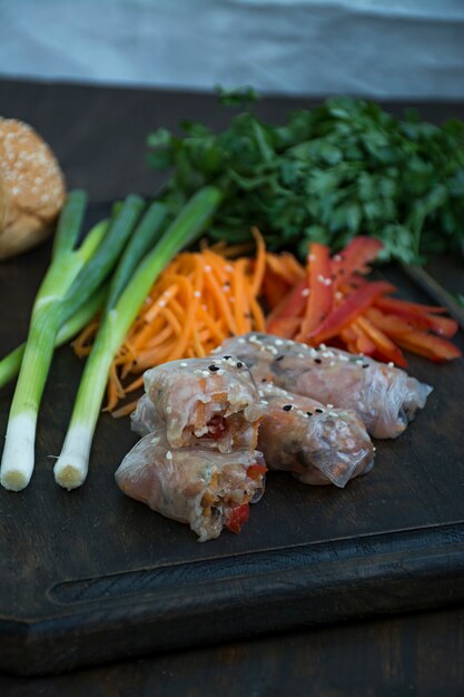 Spring roll with meat and vegetables served on a cutting board.