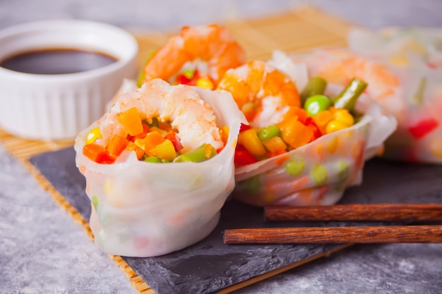 Spring rolls with vegetables and shrimps in rice paper on the black plate