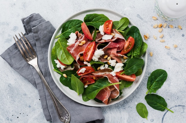 Spring Salad with spinach, cherry tomato, mozzarella, pine nuts and ham  