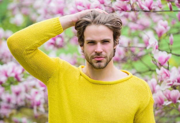 Spring season Botany and nature Happy spring concept Hipster enjoy blossom aroma Springtime concept Unshaven man sniff bloom of magnolia Man flowers background defocused Spring beauty