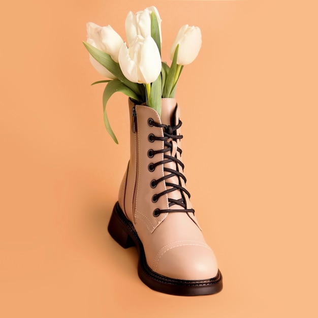 Spring shoes. Boot with white tulips on a beige background