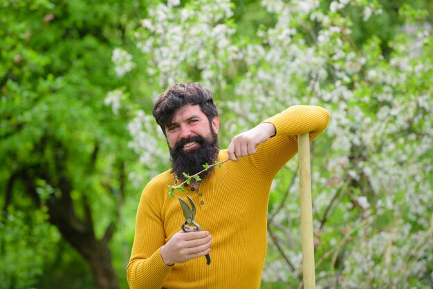 Spring smiling man in garden plants garden scissors gardening ecofarm work in garden bearded man