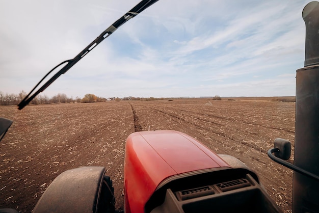 Photo spring sowing season farmer with a tractor sows corn seeds on his field planting corn with trailed planter farming seeding the concept of agriculture and agricultural machinery