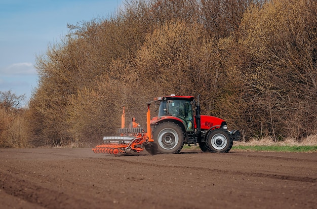 Spring sowing season Farmer with a tractor sows corn seeds on his field Planting corn with trailed planter Farming seeding The concept of agriculture and agricultural machinery