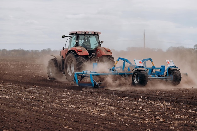 Spring sowing season farmer with a tractor sows corn seeds on\
his field planting corn with trailed planter farming seeding the\
concept of agriculture and agricultural machinery