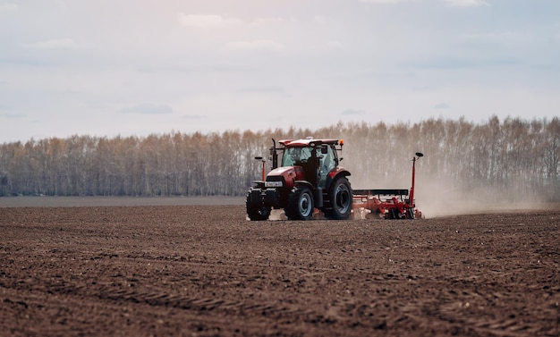 Spring sowing season Farmer with a tractor sows corn seeds on his field Planting corn with trailed planter Farming seeding The concept of agriculture and agricultural machinery