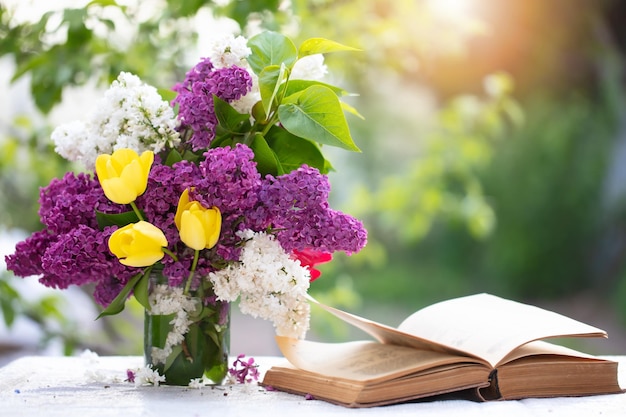 Spring or summer background A bouquet of lilacs and an old book lit by sunlight